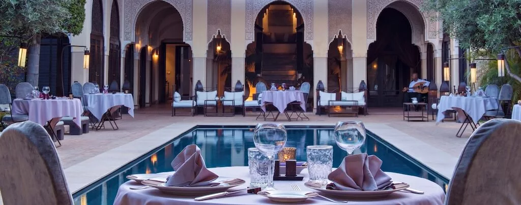 ODM-Luxury-Morocco a table set for two in a luxurious riad in Morocco with a swimming pool in the middle of the courtyard