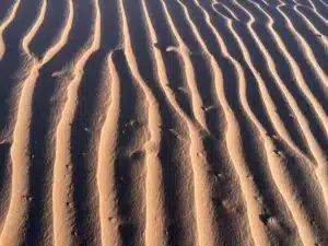 An aerial view of the Saharan dunes with wavy patterns that you will witness on the custom and shared tours by Open Doors Morocco