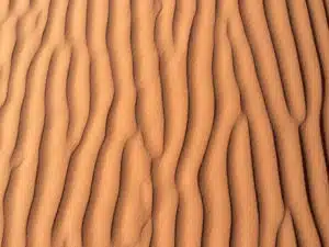 An aerial view of the Saharan dunes with wavy patterns that you will witness on the custom and shared tours by Open Doors Morocco