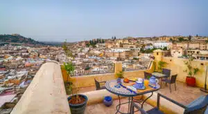 A panoramic view of Fes seen from a rooftop terrace with a table set for a breakfast, such as you can enjoy on the Open Doors Morocco's multi-day tour packages