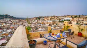 A panoramic view of Fes seen from a rooftop terrace with a table set for a breakfast, such as you can enjoy on the Open Doors Morocco's multi-day tour packages