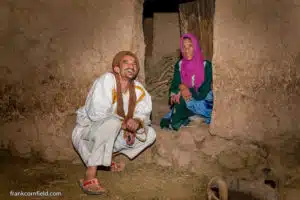 Aisha and Mustapha in Tamnougalt, kneeling together in a doorway of a traditional mud house