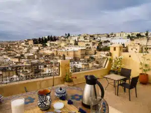 A panoramic view of Fes seen from a rooftop terrace with a table set for a breakfast, such as you can enjoy on the Open Doors Morocco's multi-day tour packages