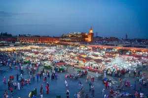 Vibrant evening market at Jemaa el-Fnaa square in Marrakech, Morocco, bustling with food stalls and shoppers. A must-visit during our private and share tours of Morocco.