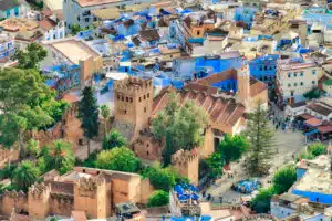 View of the blue-washed city of Chefchaouen with its blue and white buildings. Perfect for a picturesque stop on our North to South tour of Morocco.