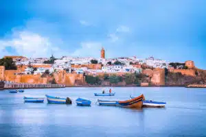 View of Rabat, Morocco's capital, with traditional white and blue buildings along the waterfront and boats in the foreground, which you'll visit on Open Doors Morocco's tours.