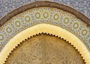 An arch with intricate Moroccan architecture with traditional geometric patterns and detailed carvings, representing cultural heritage that you will explore on our tours.