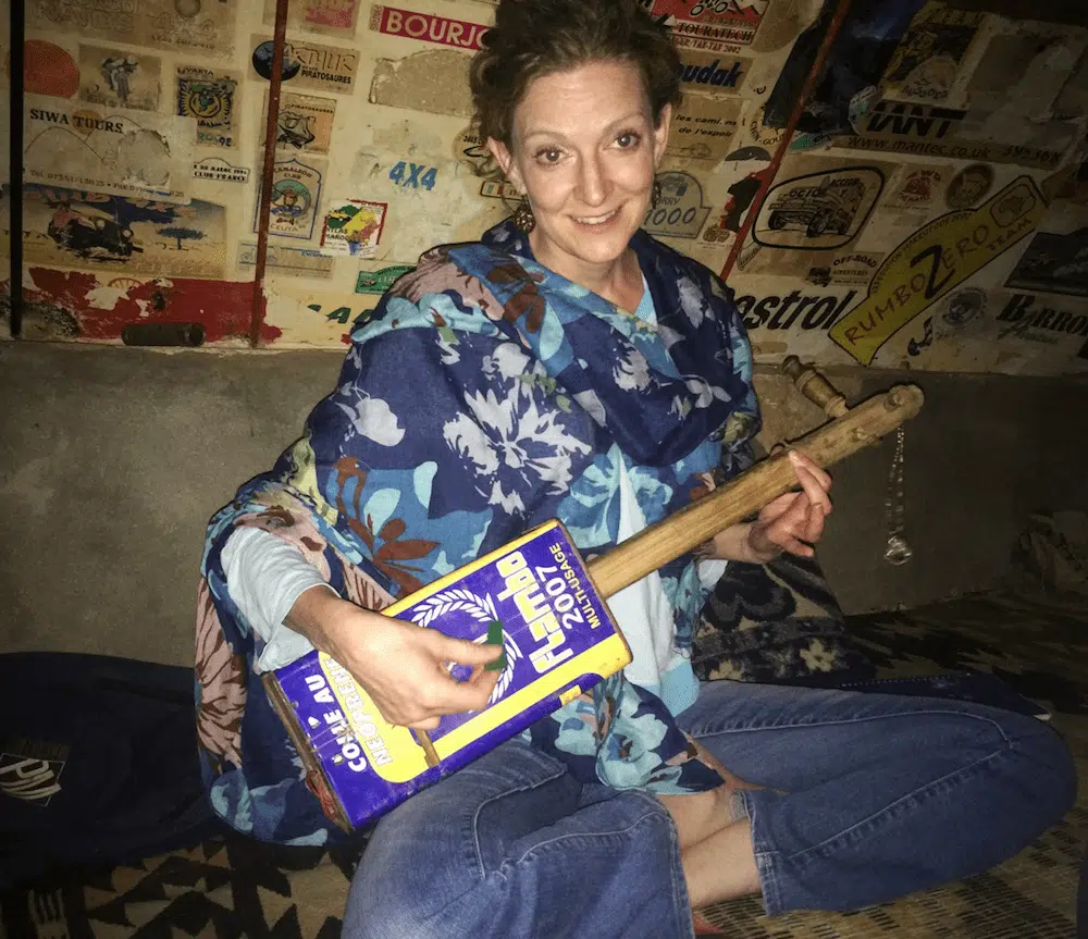 The Open Doors Morocco's founder Nancy Yee holding a homemade Moroccan guitar