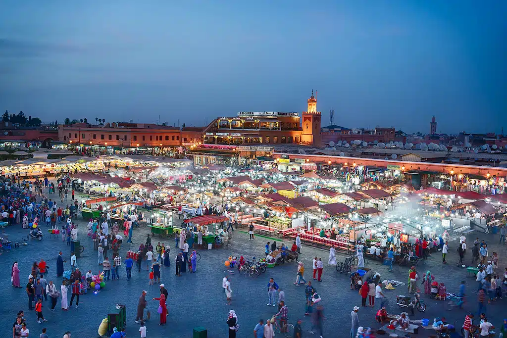 a beautifully lit central market in Marrakech seen from a higher point around the hour of sundown