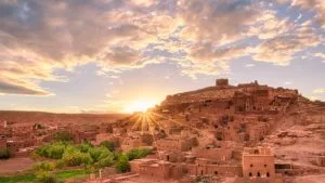 the fortified village of Ait Ben Haddou, one of Morocco's most prominent historical sites, illuminated by the sun setting in the background