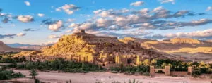 the ancient fortified village of Ait Ben Haddou illuminated by the setting sun as seen from an opposing hill