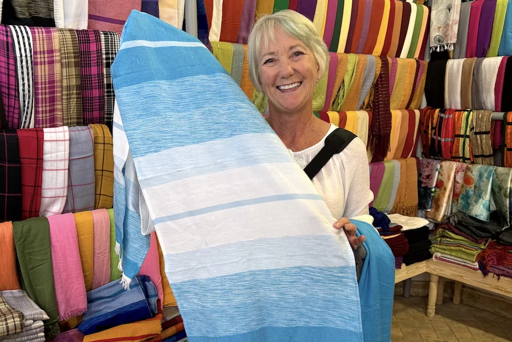 a blond woman holding a piece of blue and white piece of textile at the Bougueddach Collective, the weaving souk of Fes