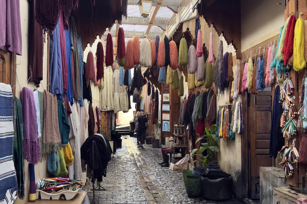 a corridor full of colorful cloths hanging from the ceiling in the dyers district of Souk Sebbaghine