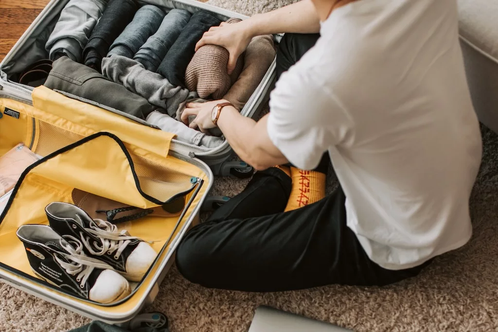 a man seen from behind as he's packing his clothes into a suitcase, ready for his trip to Morocco