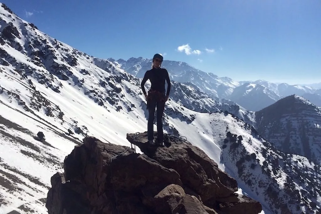 a woman standing on top of a rock and posing for a picture in the Moroccan Atlas Mountains