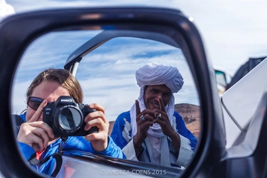 a local tour guide in Morocco helping his guests take the best shot in her rear-view mirror
