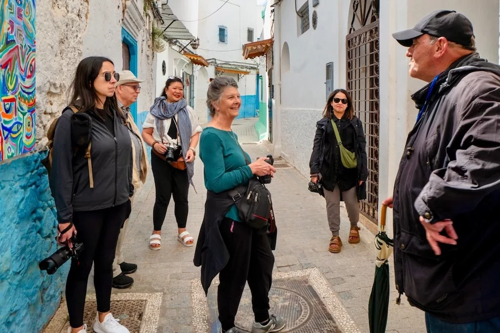 a group of travelers in Morocco talking to their local tour guide during a city tour in the colorful streets of Morocco