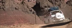 A white 4WLD car driving on a dirt road in the mountains of Morocco