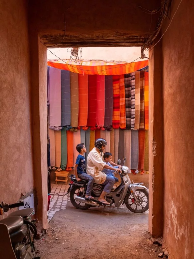 one of the best tips that you'll find in this Morocco travel photography guide is to frame your picture, just as in this image showing a man with two children on a bike seen through a door frame