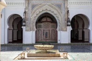 inside the courtyard of the Al Qarawiyyin University in Fes, with a view of intricately decorated entrance