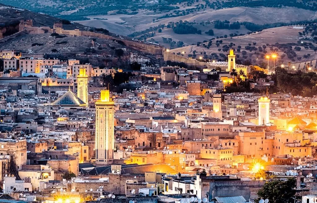 The city of Fes in Morocco seen from above at night, with the historical medina dominating the view.