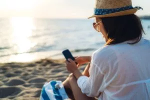 A woman at the beach in Morocco texting her family and friends on her phone