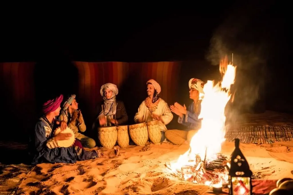Bedouins sitting around the fire at night, playing drums and singing songs together with their guests.