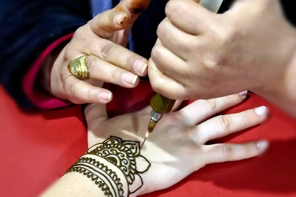 A female traveler getting a henna tattoo from a local woman in the Henna Art Cafe in Marrakech.