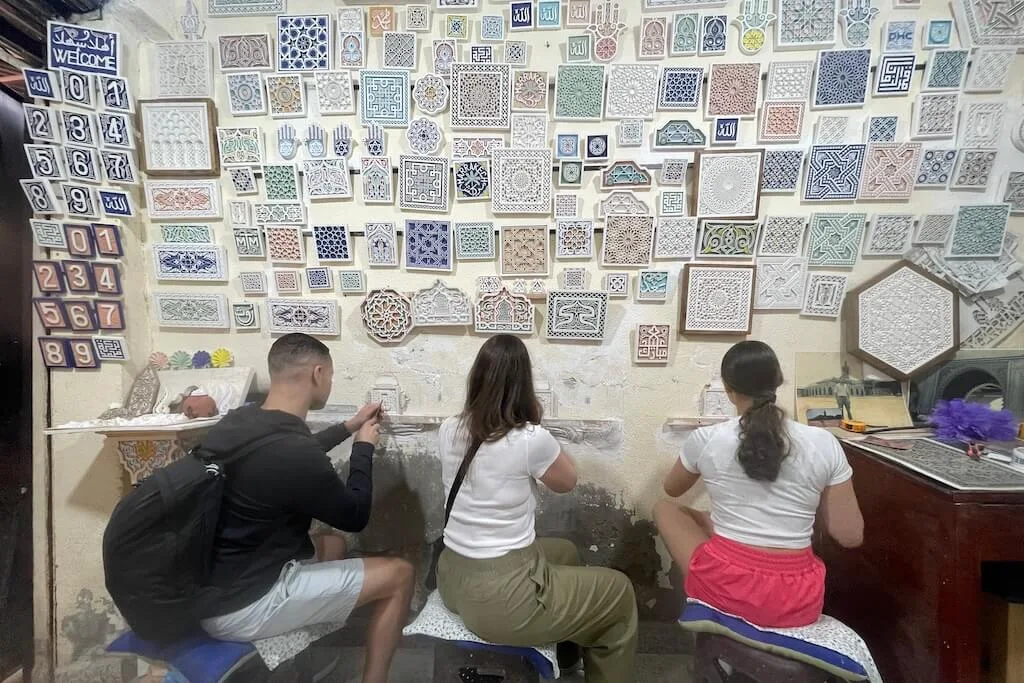 A family of travelers learning how to carve in plaster during a workshop in a local art studio.