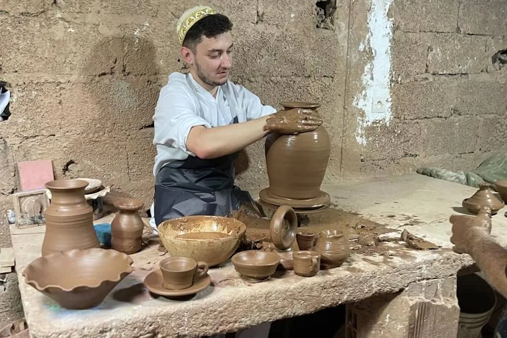 A local artisan in the act of making pottery during a workshop with his guests.