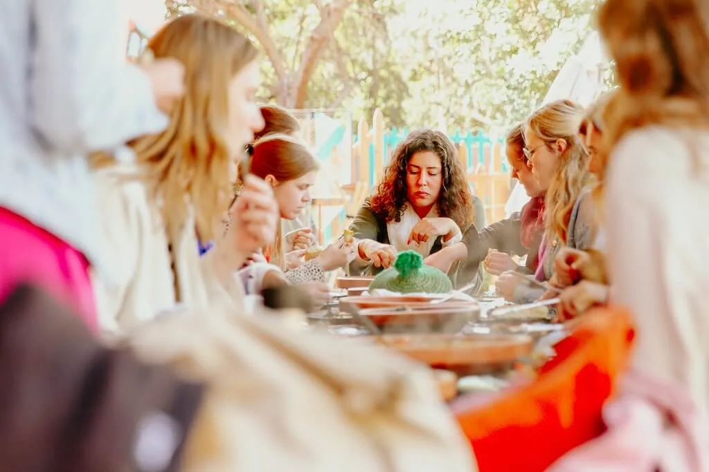 Visitors at the Amal center in Marrakech sitting around a table, sharing a meal after a cooking class.