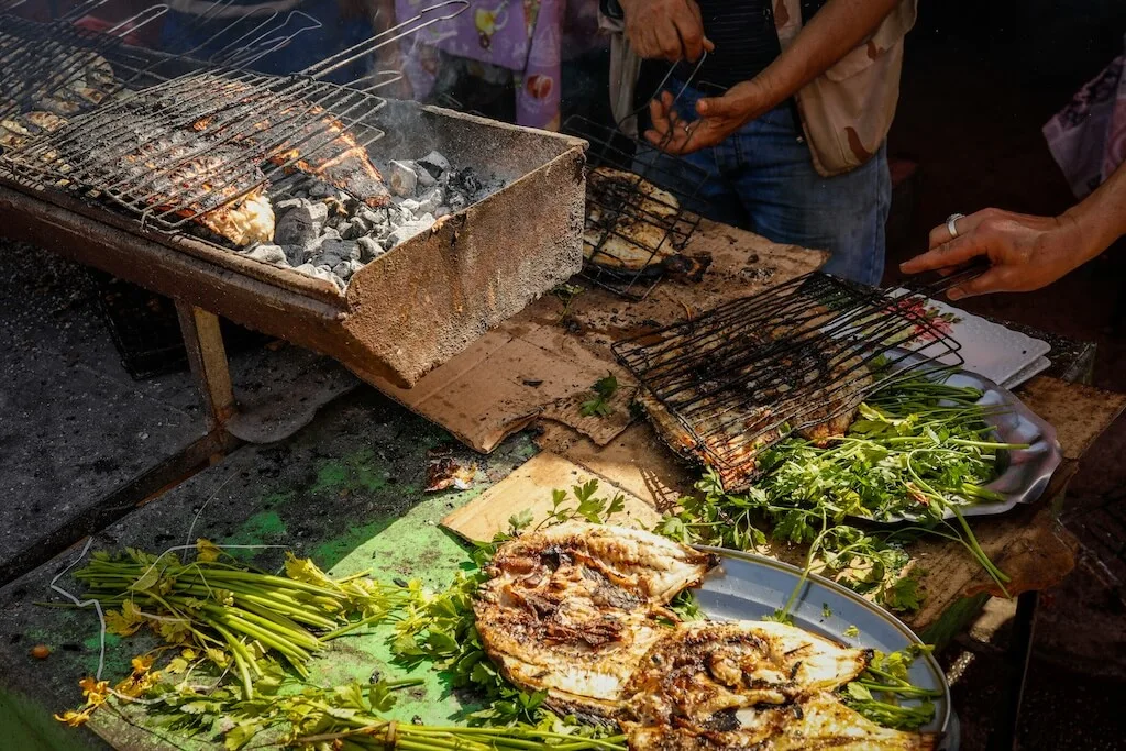 Fresh fish being grilled on the street in Essaouira with green herbs and lemon.