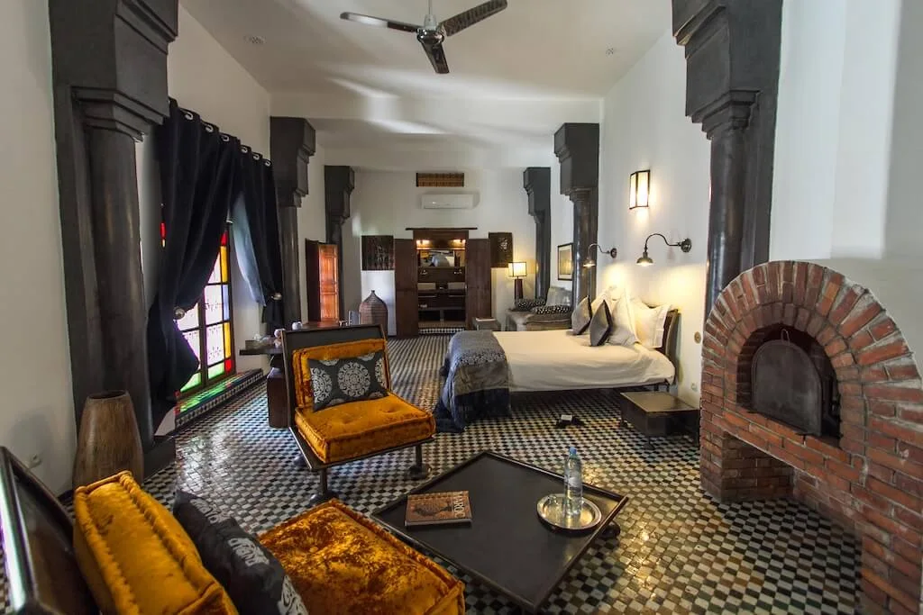 Inside one of the rooms at Riad Laaroussa, one of our favorite places to stay in Fes, with tiled floor, fireplace, living-room seating and a king-size bed.