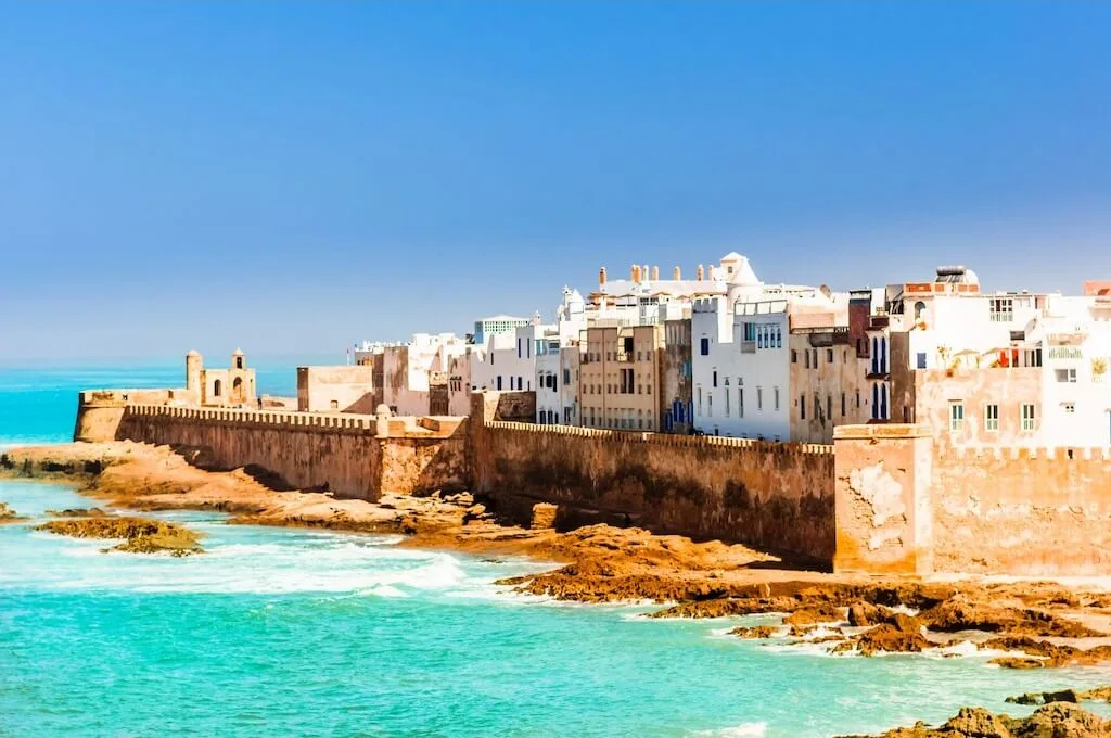 The walls of Essaouira perched above the turquoise waters of the Moroccan coast, one of the most romantic sights of all Morocco.