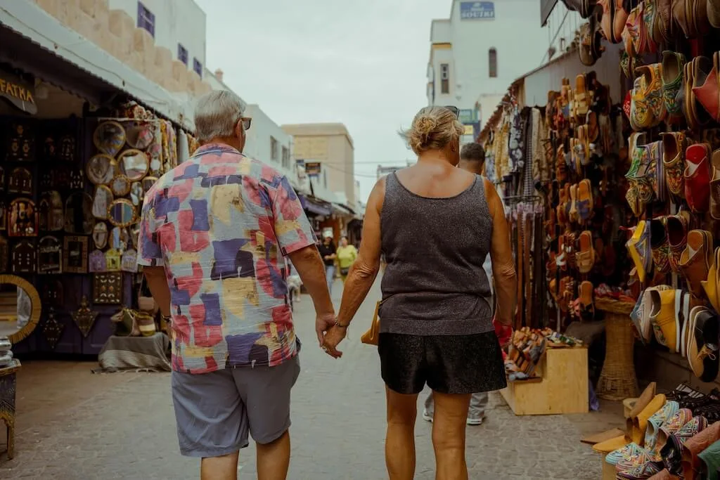 An older couple walking through the medina in Morocco, getting lost while holding hands and sharing the adventure.