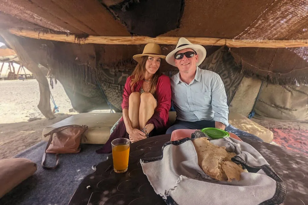 A couple posing for a picture inside a bedouin tent in the Sahara, experiencing the Moroccan idea of romance first hand.
