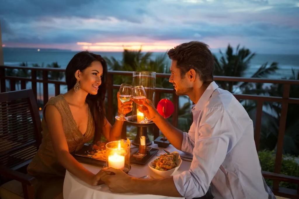A couple sharing a rooftop dinner in Marrakech, holding hands while looking into each other's eyes.