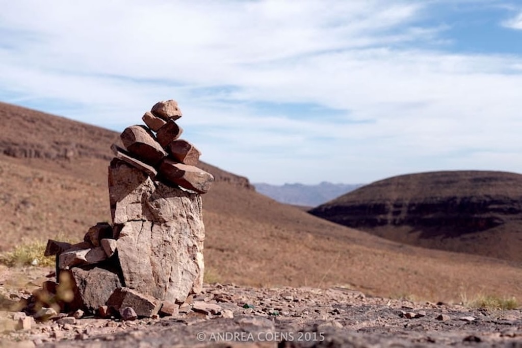 a pile of stones in the foreground and a beautiful Moroccan landscape in the background