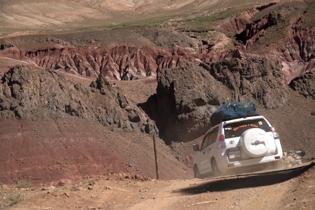 a private 4x4 car driving on a dirt road in the mountains in Morocco