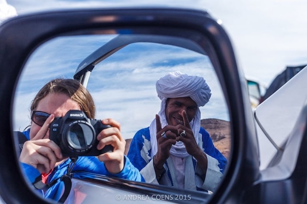 a local tour guide in Morocco helping his guests take the best shot in her rear-view mirror