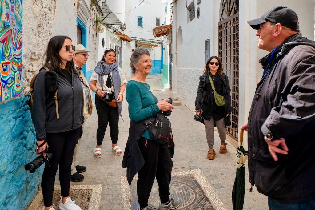 a group of travelers in Morocco talking to their local tour guide during a city tour in the colorful streets of Morocco